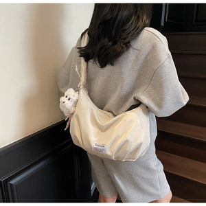 Detail of cream nylon crescent shoulder bag with plush puppy pendant and brand tag