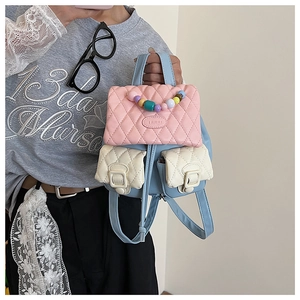 Detail of a mini backpack featuring quilted textures, pastel colors, and beaded handle