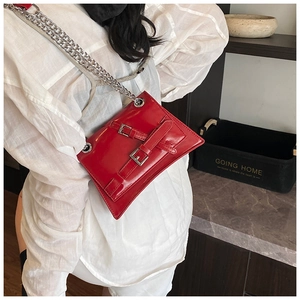Detail of red glossy leather shoulder bag with silver chunky chain and buckle straps