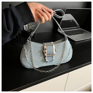 Detail of light blue denim hobo bag featuring frayed edges and silver buckle closure