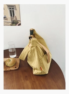 Nahaufnahme gelbe Karo-Umhängetasche mit verstellbarem Gurt auf einem Holztisch