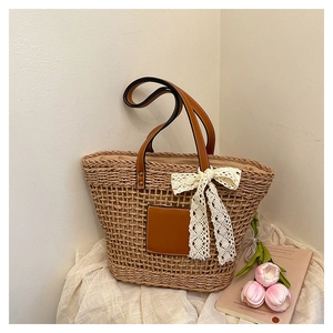 Macro detail of natural straw woven tote bag with brown leather patch and white lace bow