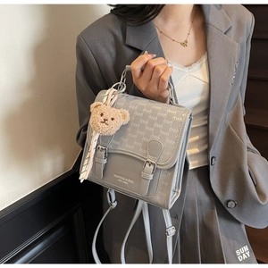 Détail d'un sac à dos gris imperméable avec breloque ours et motif de lettres