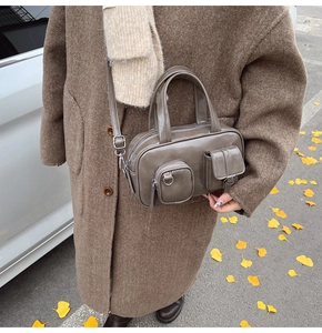 Close-up of a taupe Boston bag featuring functional outer pockets and an adjustable strap