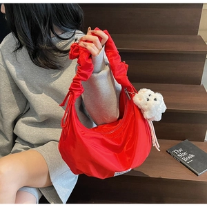 Close-up of a red nylon dumpling bag featuring a pleated handle and cute puppy charm