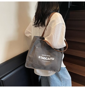 Detail of dark grey canvas tote bag with brown leather straps and printed graphic design