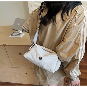 Detail showing the textured nylon fabric and circular logo of the white crossbody bag