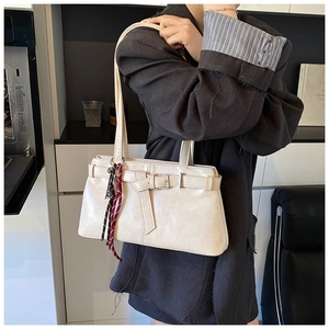 Detail of cream white PU shoulder bag with metal buckle and red striped scarf decoration