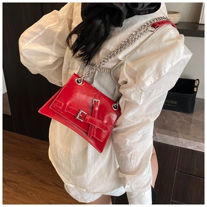 Detail of red glossy geometric handbag with silver metal buckles and chain strap