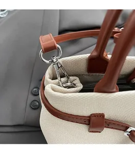 Detail of canvas bucket bag with brown leather trim and polished silver hardware