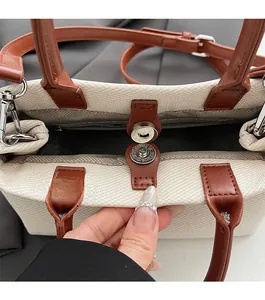 Detail of canvas bucket bag showing magnetic snap closure and leather handle attachment