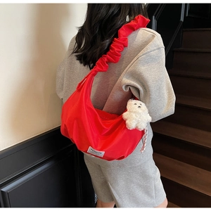 Red nylon dumpling bag with pleated strap and bear charm worn by a model