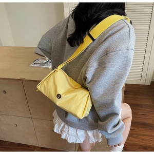 Rear view of a model wearing the yellow nylon crossbody bag with a wide fabric strap