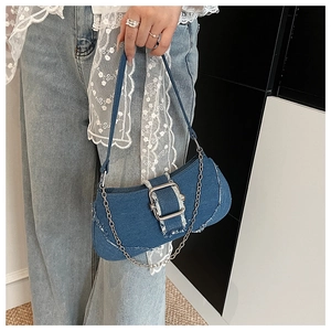 Detail of vintage denim underarm bag with silver square buckle and frayed edges