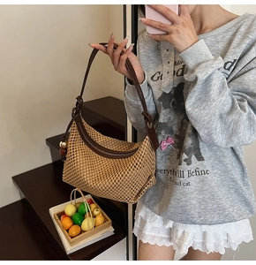 Détail du sac demi-lune en paille tressée avec bandoulière en cuir et boule métal