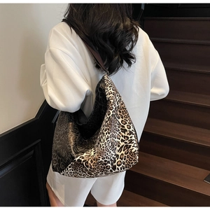 Detailed back view of a large leopard print tote bag with brown shoulder strap on a model