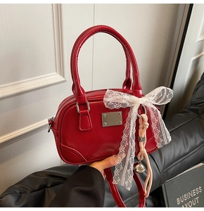 Detailansicht der roten Lackleder-Tasche mit Spitzenschleife und Glockenanhänger