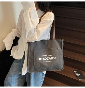 Detail of large canvas tote bag with brown leather shoulder strap and logo pocket