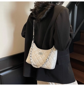 Detail einer weißen Stepptasche mit silberner Kette und metallischem Drehverschluss