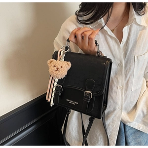 Détail du sac à dos en cuir noir imperméable avec motif monogramme et pendentif ours