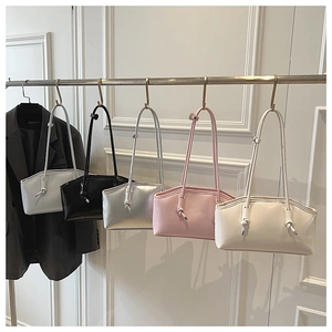 Selection of five stylish underarm bags in various colors on minimalist store display