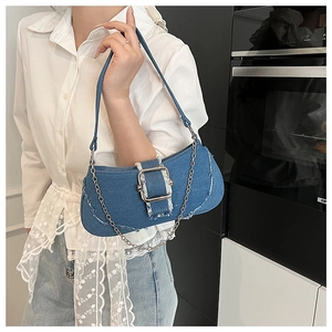 Detail of blue denim shoulder bag with silver buckle and distressed frayed edges