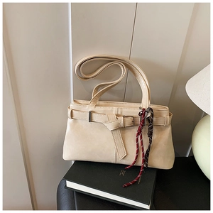 Detail of off-white faux leather handbag featuring a belt buckle and tricolor braided cord