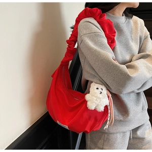 Detail of red crescent shoulder bag with ruffle strap and plush bear charm decoration