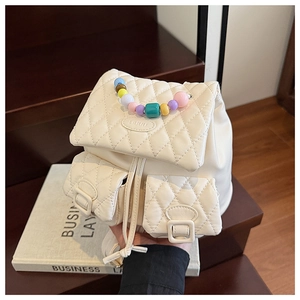 Detail of quilted beige backpack featuring colorful candy-colored beads handle and metal logo