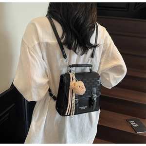 Détail d'un sac à dos noir étanche en cuir avec boucles et peluche sur mannequin de dos