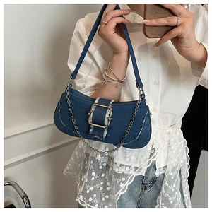 Macro detail of retro denim baguette bag with gold buckle and distressed frayed edges