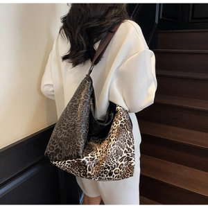 Detail of a large leopard print crossbody hobo bag with contrast stitching on the strap