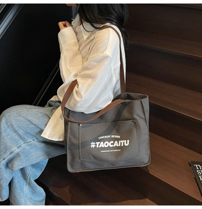 Detail of dark grey canvas tote bag with brown leather straps and front pocket