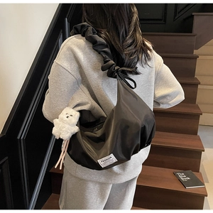 Detail of black nylon dumpling bag with pleated shoulder strap and white bear charm