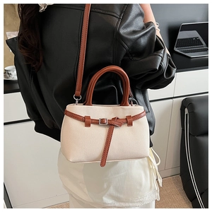 Detail of cream woven fabric and brown leather straps on a stylish bucket handbag