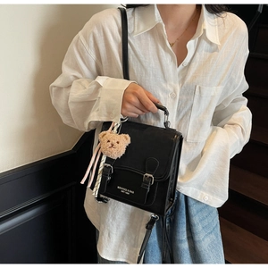 Détail du sac à dos en cuir noir imperméable avec boucles doubles et charm ours en peluche