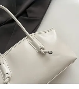 Close-up of knotted shoulder strap and textured cream leather finish on the tote bag