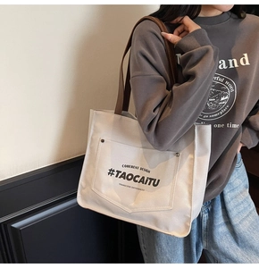 Detail of canvas tote bag showing contrast brown handles and Coherent Design print
