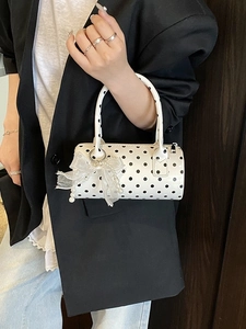 Sac cylindre à pois avec nœud en dentelle et perles porté par un mannequin chic