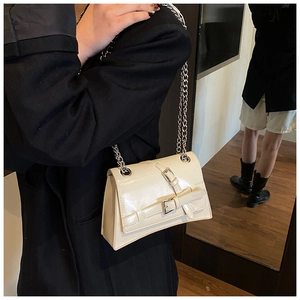 Detail of off-white glossy faux leather shoulder bag with silver chain and buckles