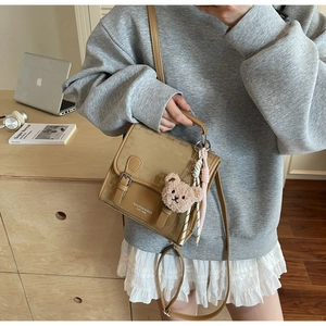 Vue détaillée du sac à dos en cuir synthétique marron avec breloque ours et boucle métal