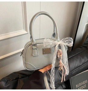 Nahaufnahme der hellblauen Lackleder-Handtasche mit Spitzenschleife und Anhänger