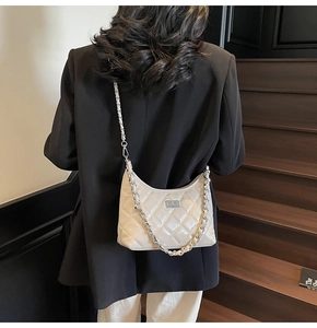 Cremefarbene Stepptasche mit Silberkette und Metallverschluss am Modell getragen