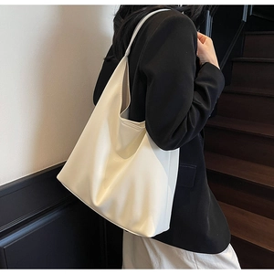 Minimalist white PU leather tote bag shown on shoulder in a stylish urban setting