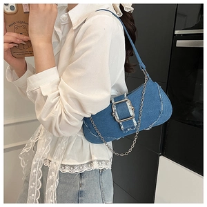 Detail of denim shoulder bag with chunky metal chain and silver buckle on model