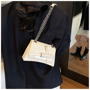 Detail view of cream crossbody bag with silver chain strap and unique asymmetric base design