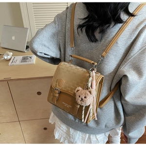 Détail d'un sac à dos imperméable marron avec monogramme et charm ours en peluche