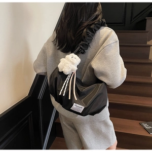 Detail of black pleated cloud bag with fashion instinct label and plush charm