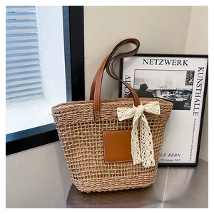 Close-up of woven straw tote bag texture with white lace bow and leather handles
