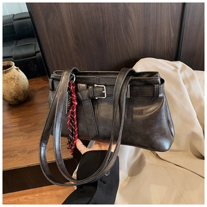 Detail of dark brown vintage leather tote bag with decorative buckle and silk scarf